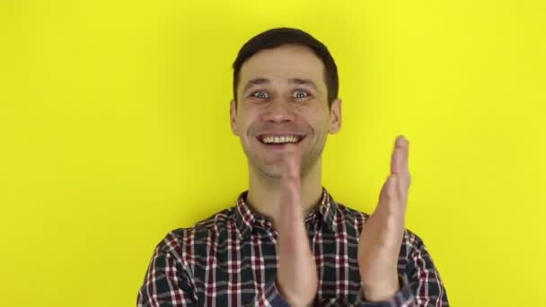 A funny handsome guy actively expresses his enthusiasm and claps his hands. A portrait of a young guy, he expresses his enthusiasm and actively applauds. Portrait on a yellow background. — Stock Video