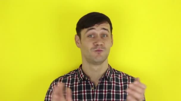 A Funny, handsome guy claps his hands sarcastically. Portrait of a young guy, shakes his head negatively and applauds with sarcasm.Portrait on a yellow background. — Stock Video