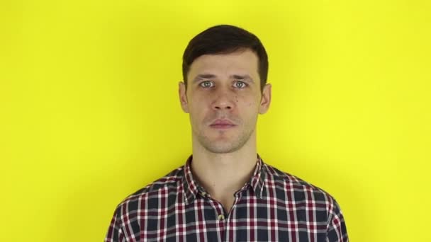 Funny handsome guy shows thumb down expressing his disapproval. Portrait on a yellow background. — Stock Video