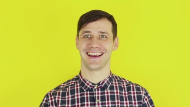 Funny handsome guy smiles and shows thumb up. Portrait on yellow background. — Stok video