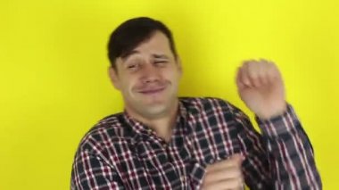 Komik, yakışıklı bir adam komik dans ediyor. Genç bir adamın portresi, neşe ifade eder ve komik dans eder. Sarı arka planda bir portre..