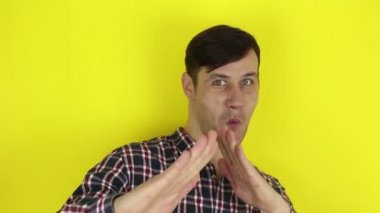 Komik, yakışıklı adam komik bir karateyi canlandırıyor, elleriyle havaya yumruk atıyor. Genç bir adamın portresi, karateyi taklit eden bir dövüşü komik tasvir eder. Sarı arkaplanda bir portre.