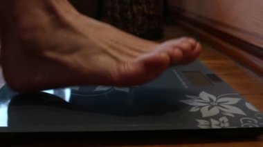 Genç bir kız tartıda duruyor ve ağırlığını kontrol ediyor. Evde genç bir kız tartılıyor..