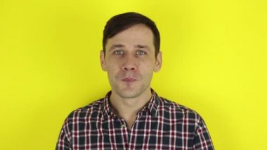 Komik, yakışıklı bir adam gülümseyip kız arkadaşına hava öpücüğü yolluyor. Genç bir adamın portresi, gülümsüyor ve kameraya hava öpücüğü gönderiyor. Sarı arkaplanda bir portre.