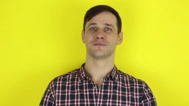 Gülümseyen ve kalp işaretini elinden katlayan komik, hoş bir adam. Genç bir adamın portresi, gülümsedi ve ellerinden bir kalp işareti gösterdi. Sarı arkaplanda bir portre.