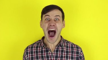 Komik, yakışıklı bir adam, öfkesini belli ediyor ve güçlü çığlıklar atıyor. Genç bir adamın portresi, bağırıyor ve öfkeyi yozlaştırıyor. Sarı arkaplanda bir portre.