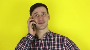 Komik, sevimli bir adam akıllı telefonuyla bir telefon görüşmesi yapıyor. Genç bir adamın portresi, aktif olarak cep telefonuyla konuşuyor. Sarı arkaplanda bir portre.