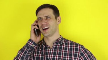 Komik, sevimli bir adam akıllı telefonuyla bir telefon görüşmesi yapıyor. Genç bir adamın portresi, aktif olarak cep telefonuyla konuşuyor. Sarı arkaplanda bir portre.