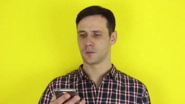 Komik, sevimli bir adam akıllı telefonuyla sosyal medyayı kurcalıyor. Genç bir adamın portresi, akıllı telefonuyla sosyal medyayı aktif olarak izliyor. Sarı arkaplanda bir portre.