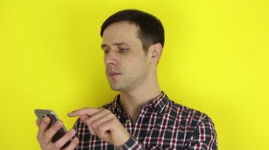 Komik, sevimli bir adam akıllı telefonuyla sosyal medyayı kurcalıyor. Genç bir adamın portresi, akıllı telefonuyla sosyal medyayı aktif olarak izliyor. Sarı arkaplanda bir portre.