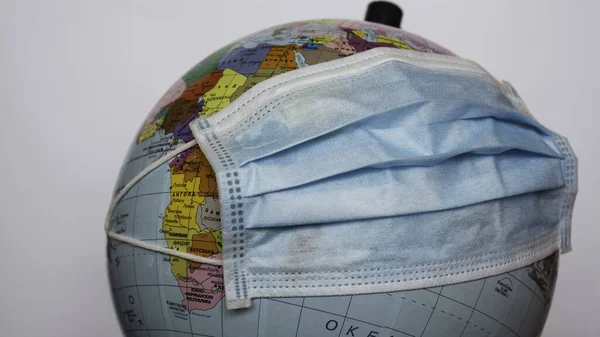 Earth globe wears a medical mask. A medical mask is worn on an earth globe. World quarantine, coronavirus pandemic. World quarantine symbol.