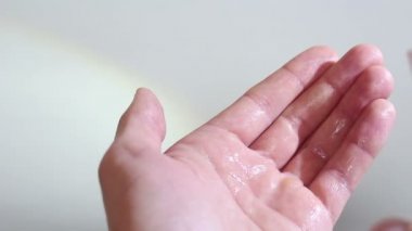 Genç bir adam ellerini antiseptikle dezenfekte ediyor. Genç adam önlem için ellerine antiseptik sıkar. Eller yukarı..