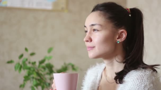 Ένα Νεαρό Ελκυστικό Κορίτσι Πίνει Καφέ Από Ένα Ροζ Φλιτζάνι — Αρχείο Βίντεο