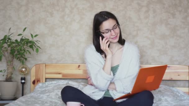 Genç Çekici Bir Kız Cep Telefonuyla Konuşuyor Bilgisayardaki Verileri Karşılaştırıyor — Stok video