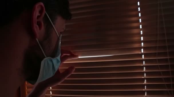 Ung Stilig Kille Ansiktsmask Tittar Genom Fönsterpersiennerna Ung Kille Medicinsk — Stockvideo