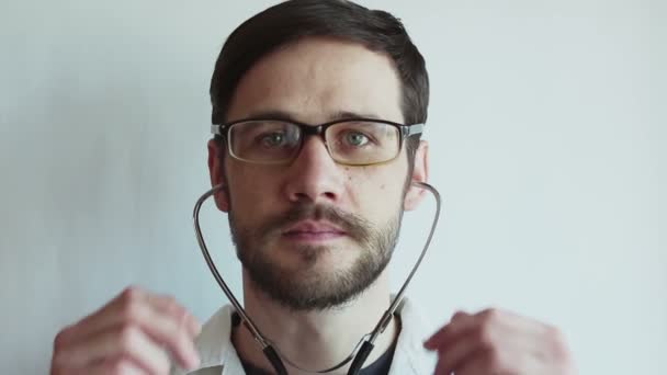 Young Handsome Doctor Wearing Glasses Smiles Broadly Takes Stethoscope Hangs — Stock Video