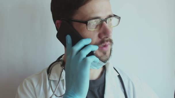 Joven Médico Guapo Con Gafas Una Mascarilla Médica Una Consulta — Vídeo de stock