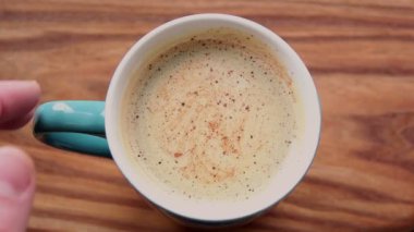 Bir erkeğin elleri bir fincan aromatik kahve tutuyor. Ahşap bir masanın üzerinde bir fincan aromatik kahve duruyor. Bir adam bir fincan kahveyle ellerini ısıtır..