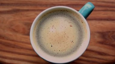 Bir erkeğin elleri bir fincan aromatik kahve tutuyor. Ahşap bir masanın üzerinde bir fincan aromatik kahve duruyor. Bir adam bir fincan kahveyle ellerini ısıtır..