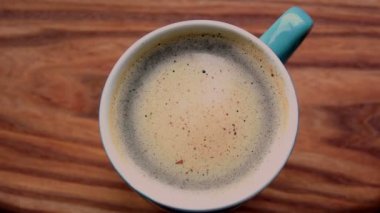 Bir adam bir fincan aromatik kahveye şeker karıştırır. Ahşap bir masanın üzerinde bir fincan aromatik kahve duruyor. Erkekler kaşıkla kahve içmeyi karıştırır..