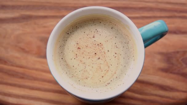 Un uomo mani sono in possesso di una tazza di caffè aromatico. Una tazza di caffè aromatico poggia su un tavolo di legno. Un uomo si scalda le mani con una tazza di caffè . — Video Stock