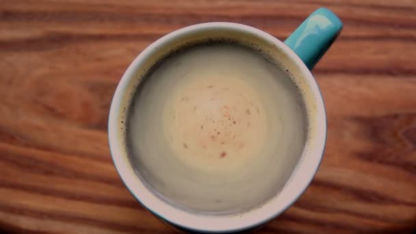 Les mains d'un homme tiennent une tasse de café aromatique. Une tasse de café aromatique se trouve sur une table en bois. Un homme se réchauffe les mains avec une tasse de café . — Video