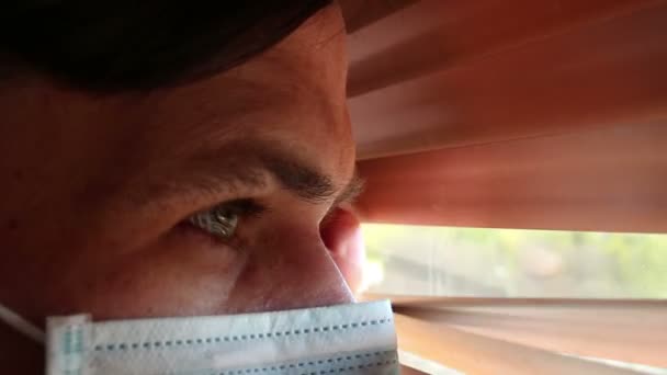 Ένας Νεαρός Όμορφος Άντρας Ιατρική Μάσκα Κοιτάει Από Παράθυρα Ένας — Αρχείο Βίντεο