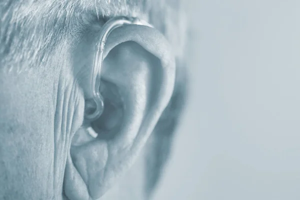 白人白人高齢者男性身に着けています現代的なデジタル補聴器で耳の中に灰色の髪 — ストック写真