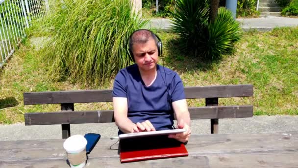 Middle-aged man works remotely in garden, in nature. — Stock Video