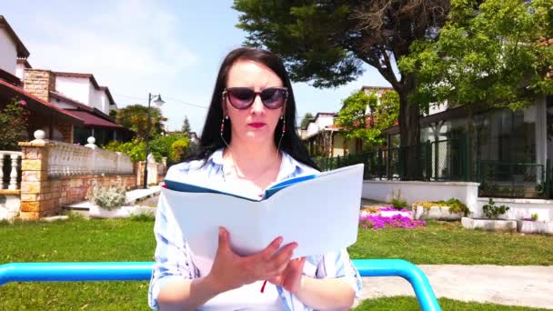 벤치 독서 책에 앉아 있는 젊은 여자. — 비디오