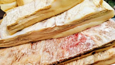 Domuz pastırması parçaları istiflenmiş ve et ambalajlarıyla tuzlanmış.