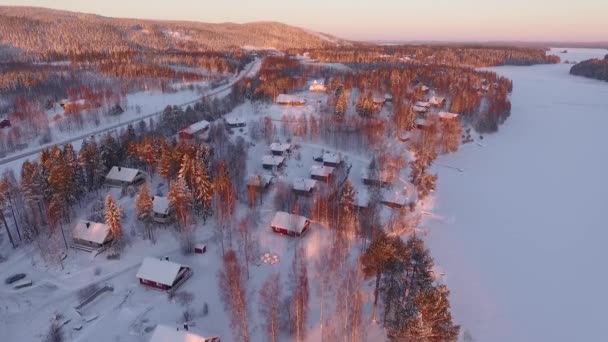 無人機が家や凍った湖を飛び越える 日没の雪はどこでも — ストック動画