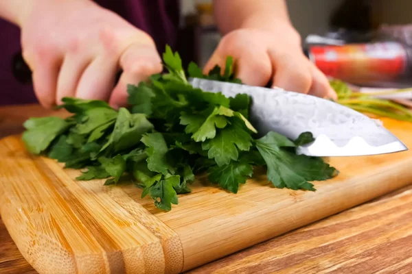 Peterselie snijden met een mes op snijplank. — Stockfoto