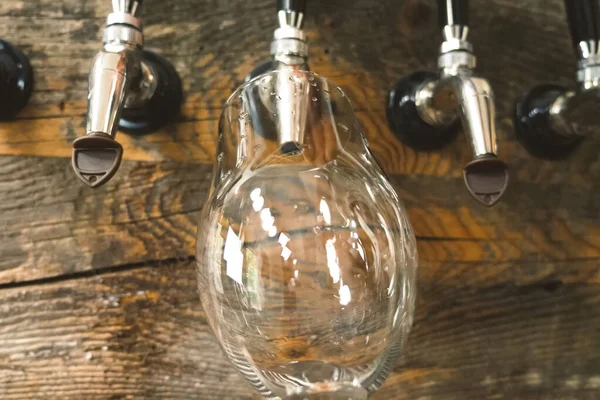 Bier in een glas gieten uit de kraan aan de bar. Bierbotteling. — Stockfoto