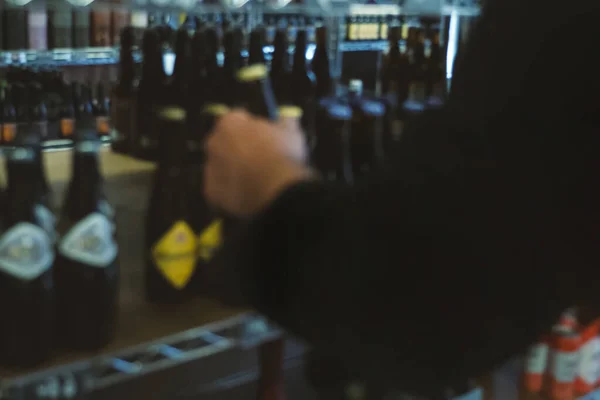 Wazig beeld, wazig, de mens kiest bier in een winkel op de toonbank. — Stockfoto