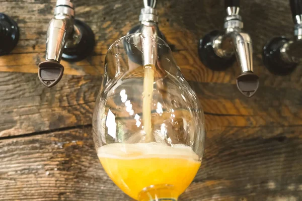 Bier in een glas gieten uit de kraan aan de bar. Bierbotteling. — Stockfoto