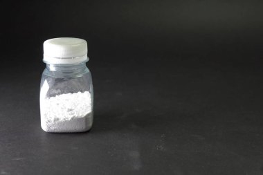 Şeffaf kavanozda beyaz toz. Masanın üzerinde beyaz toz.