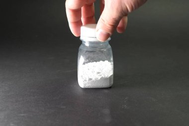 Şeffaf kavanozda beyaz toz. Masanın üzerinde beyaz toz.