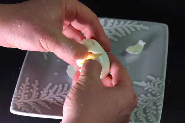 J'épluche un œuf bouilli. Un homme nettoie l'oeuf pour le petit déjeuner . — Photo