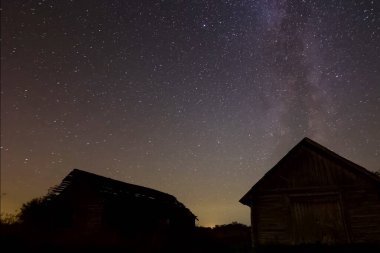 Köydeki ahşap evlerin üzerinde yıldızlı gökyüzü. Yıldızlı gökyüzü gece gökyüzündeki yıldızların ve Samanyolu 'nun arkaplan resmi.