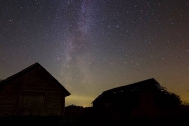 Köydeki ahşap evlerin üzerinde yıldızlı gökyüzü. Yıldızlı gökyüzü gece gökyüzündeki yıldızların ve Samanyolu 'nun arkaplan resmi.