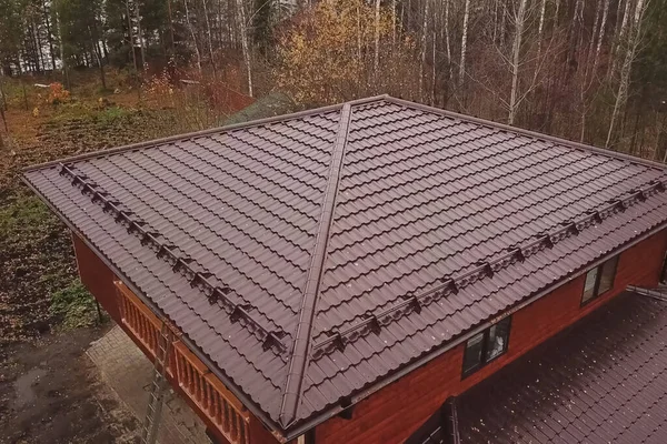 Casa com um telhado de metal marrom. Telhado de metal ondulado e metal ro — Fotografia de Stock
