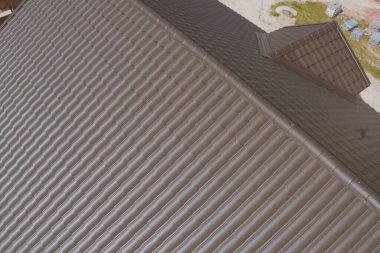 Evin çatısında kahverengi metal fayans var. Oluklu metal çatı