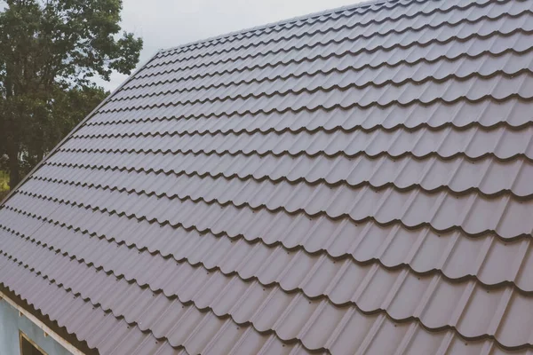 Mattonelle di metallo marrone sul tetto della casa. tetto in metallo ondulato — Foto Stock