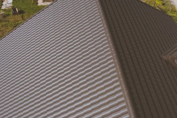 Hnědé kovové dlaždice na střeše domu. Vlnitá kovová střecha — Stock fotografie