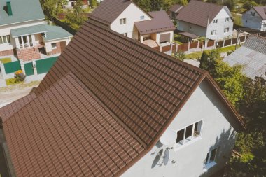 Evin çatısında kahverengi metal fayans var. Oluklu metal çatı