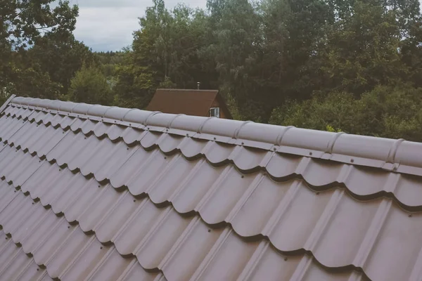 Baldosas de metal marrón en el techo de la casa. Techo de metal corrugado — Foto de Stock