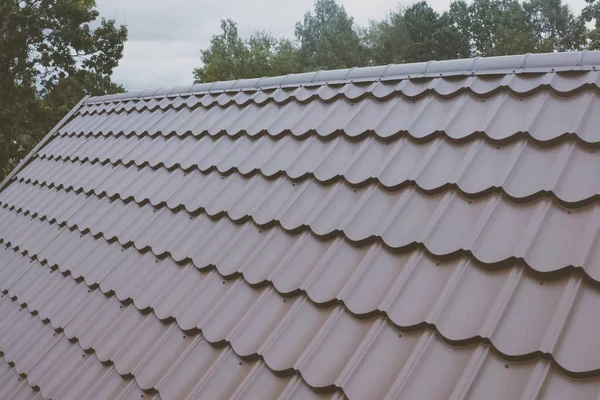 家の屋根の上に茶色の金属タイル。段ボール金属屋根 — ストック写真