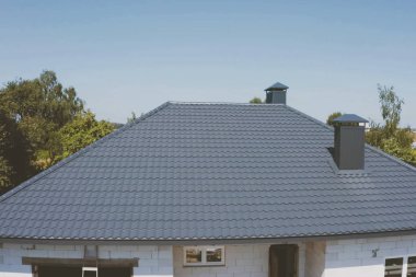 Evin çatısında gri-mavi-metal kiremitler var. Oluklu