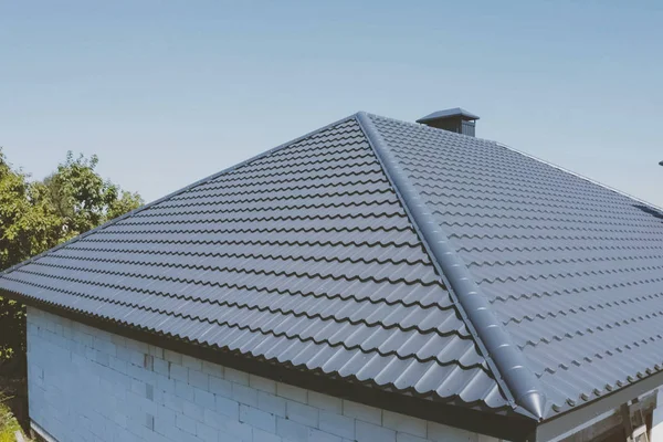 Gray-blue metal roof tiles on the roof of the house. Corrugated